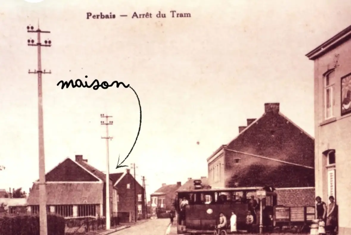 Carte postale ancienne en sépia : Perbais, l'arrêt du tram, avec la maison désignée à la main.