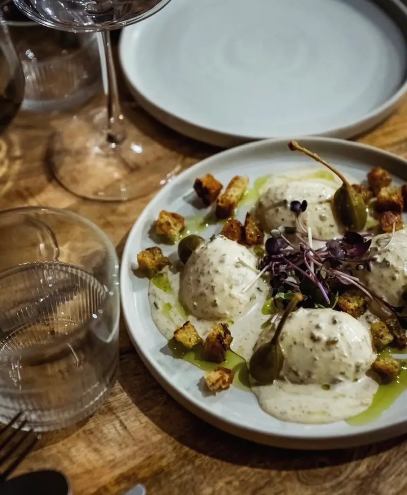 Des quenelles de fromage frais, croûtons et câpres dans une assiette creuse.